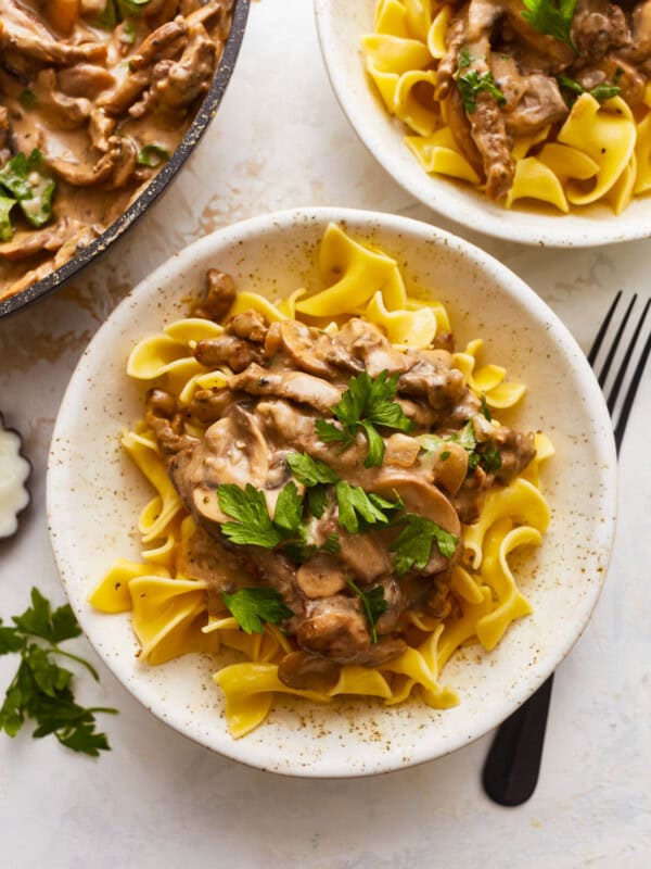 Two bowls of swedish stroganoff with mushrooms and parsley.