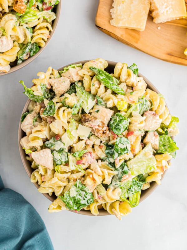 Two bowls of pasta salad with chicken and lemon.