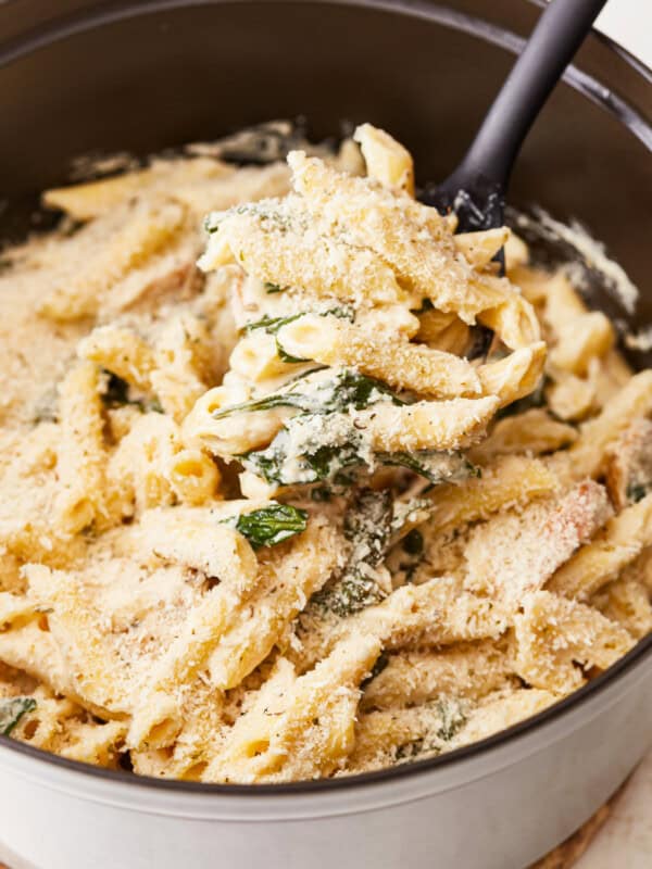 Penne pasta with chicken and spinach in a pan.