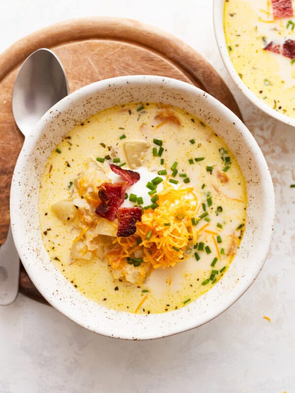 Two bowls of chowder with cheese and bacon.