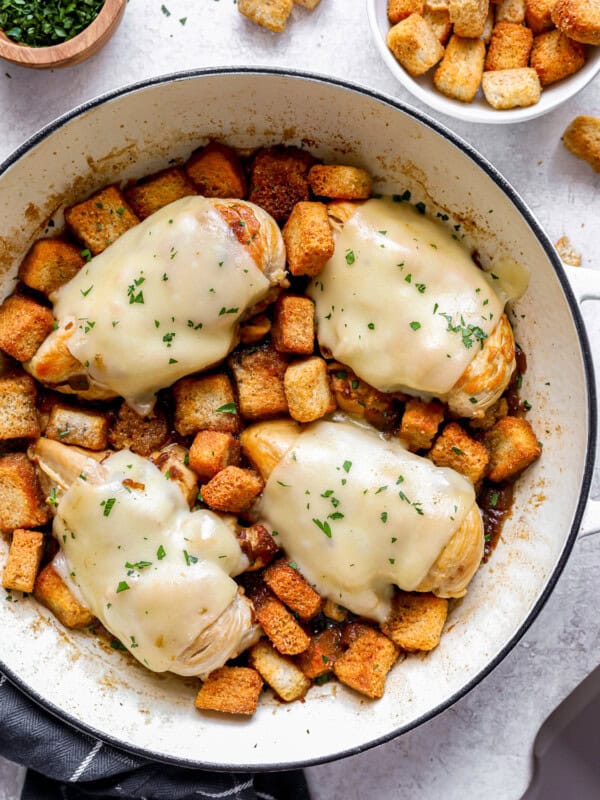 Chicken breasts in a skillet with croutons.