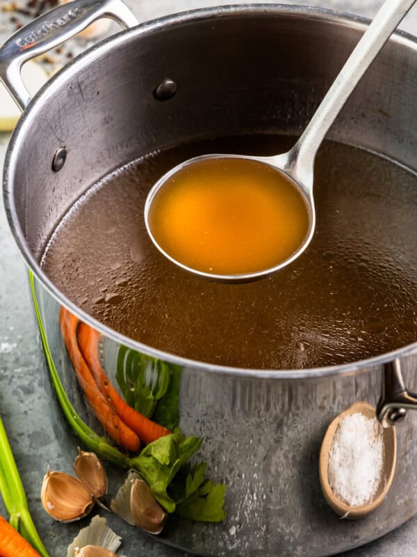 Broth in a pot with carrots and onions.