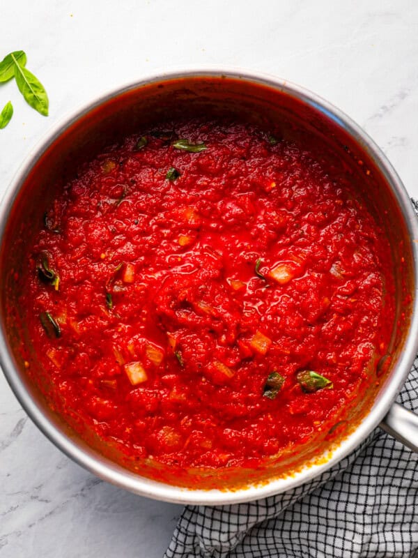 Tomato sauce in a pan with basil leaves.