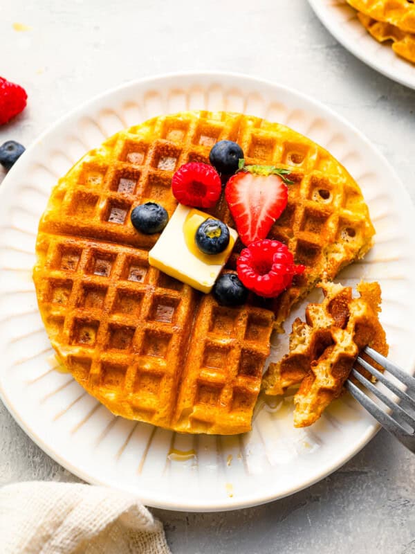 A plate of waffles with berries and a fork.