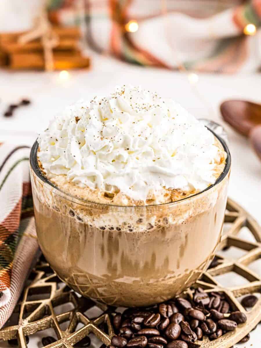 large clear mug with pumpkin spice latte topped with whipped cream