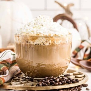 large clear mug with pumpkin spice latte topped with whipped cream