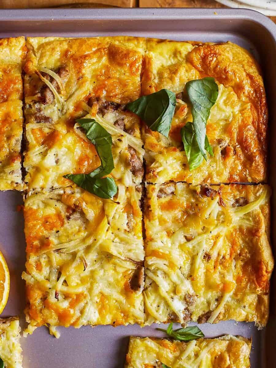 egg and sausage breakfast pizza cut into square slices.