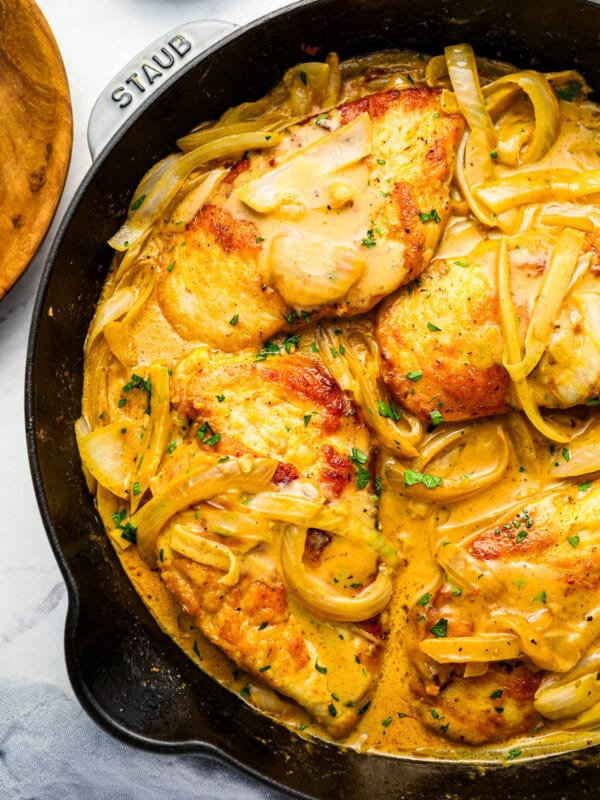 A skillet with chicken and onions in a sauce.