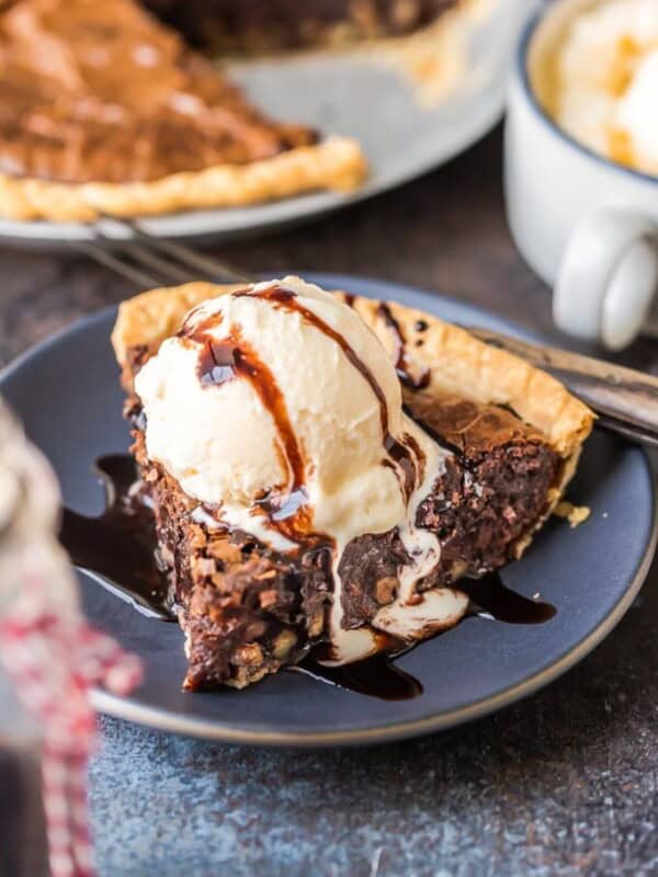 A slice of brownie pie topped with ice cream on a plate.