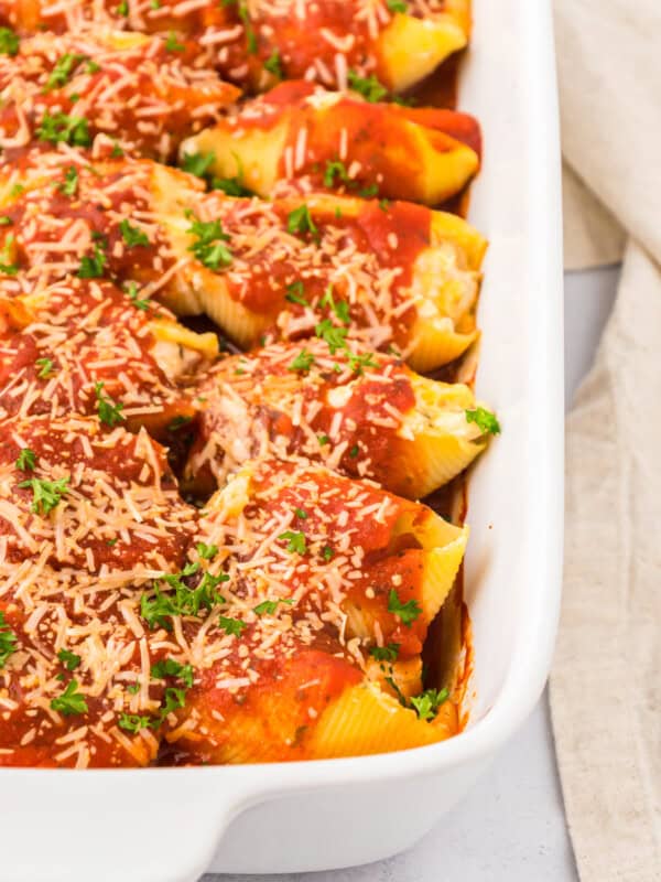 Stuffed shells with sauce and parmesan cheese in a white baking dish.