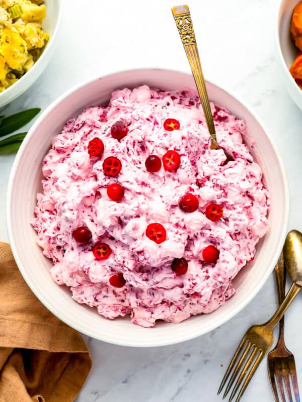 A bowl of cranberry dip with cranberries and carrots.