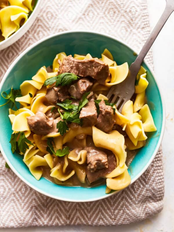 Beef stroganoff in a blue bowl with a fork.