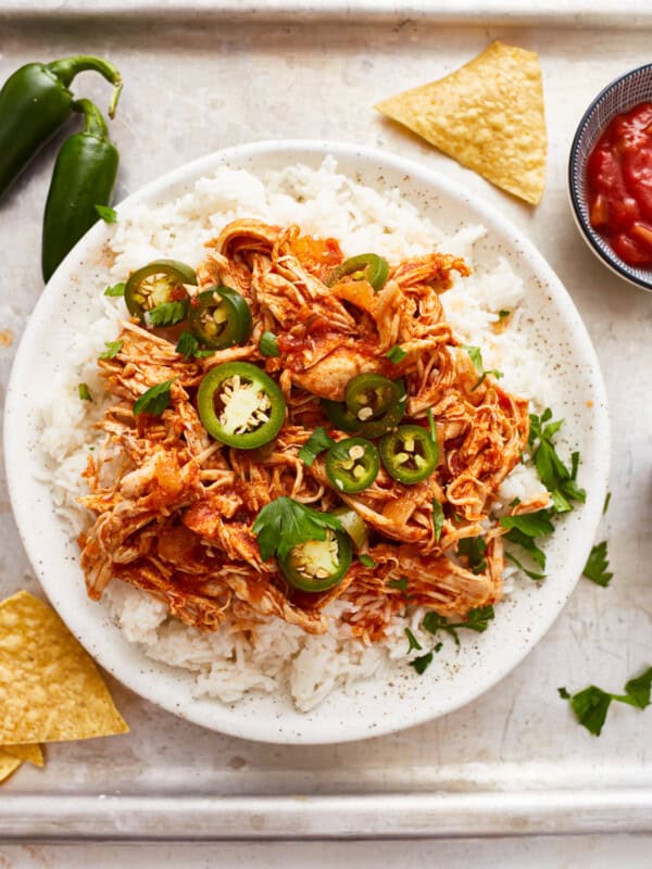 A bowl of rice with chicken and jalapenos.