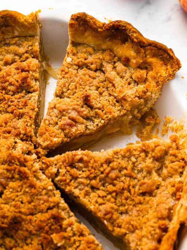 A slice of apple pie with a crumb topping on a plate.