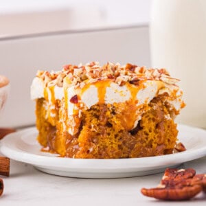 A slice of pumpkin cake on a plate next to a glass of milk.