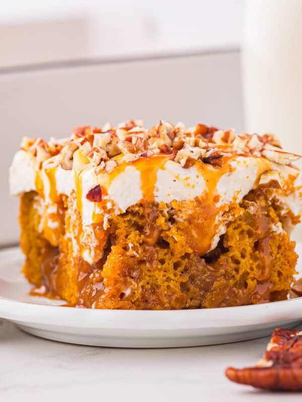 A slice of pumpkin cake on a plate next to a glass of milk.