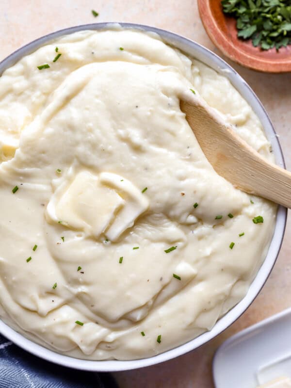 Mashed potatoes in a bowl with a wooden spoon.