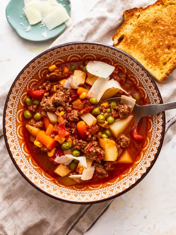 A bowl of soup with meat, vegetables and bread.