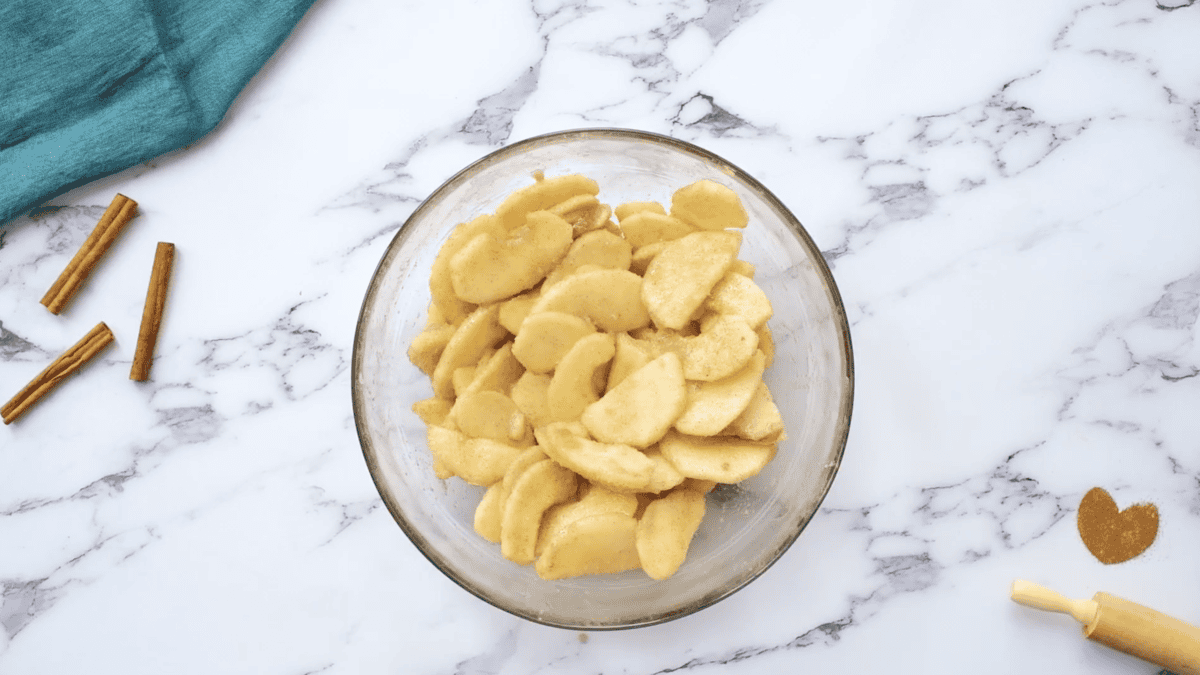 sliced apples tossed with cinnamon-sugar in a glass bowl.