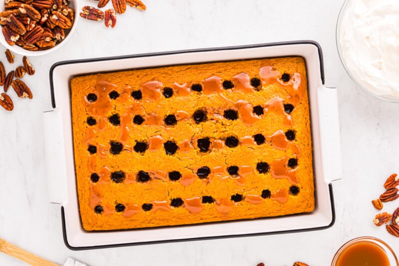 A white baking dish with a pumpkin cake and pecans.