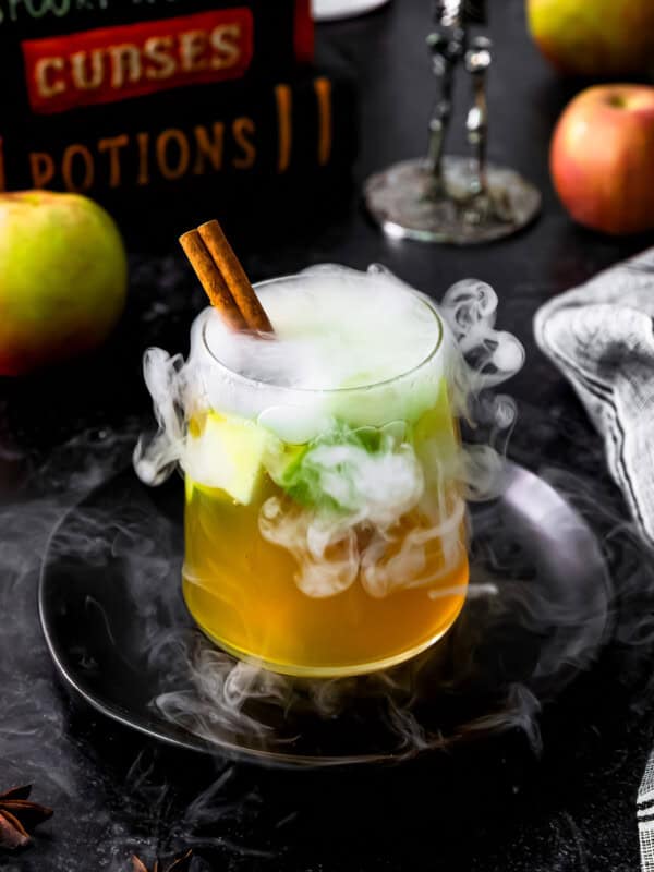 A witch's brew with apples and spices in a glass.