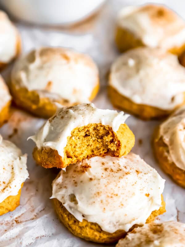 Pumpkin cookies with icing and a bite taken out.