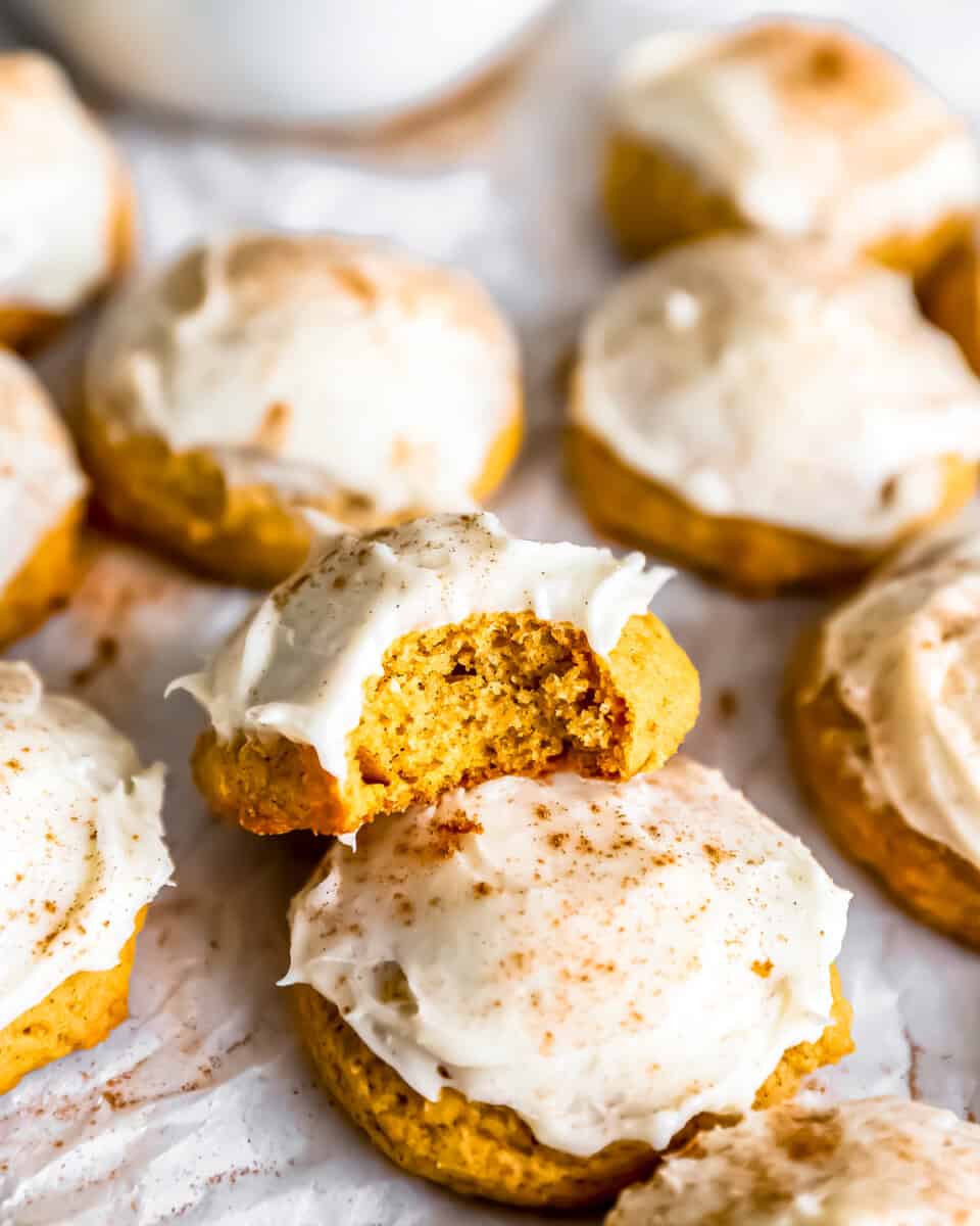 Pumpkin cookies with icing and a bite taken out.