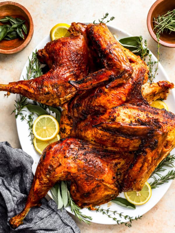 A roasted turkey on a plate with lemons and sprigs of thyme.