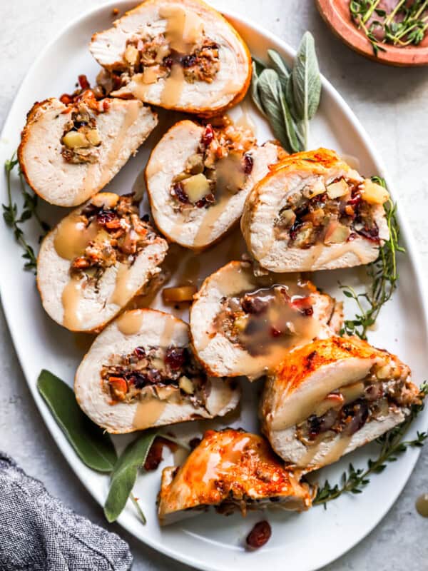 Turkey stuffed with cranberries and sage on a white plate.