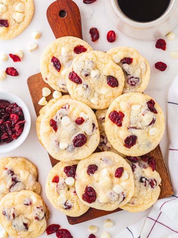 Cranberry white chocolate cookies on a cutting board with a cup of coffee.