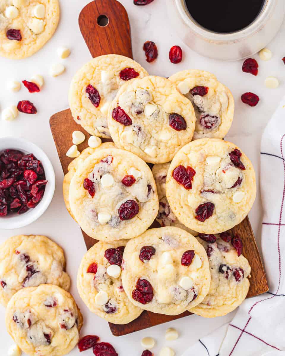 Cranberry white chocolate cookies on a cutting board with a cup of coffee.