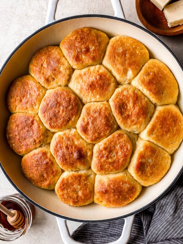 A skillet filled with biscuits and honey.