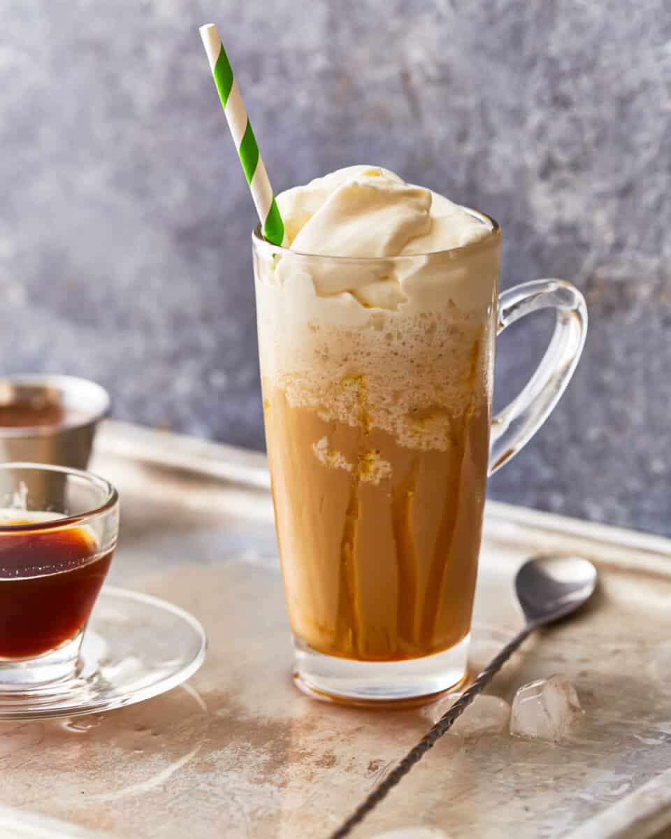 A cup of coffee with whipped cream and a straw.