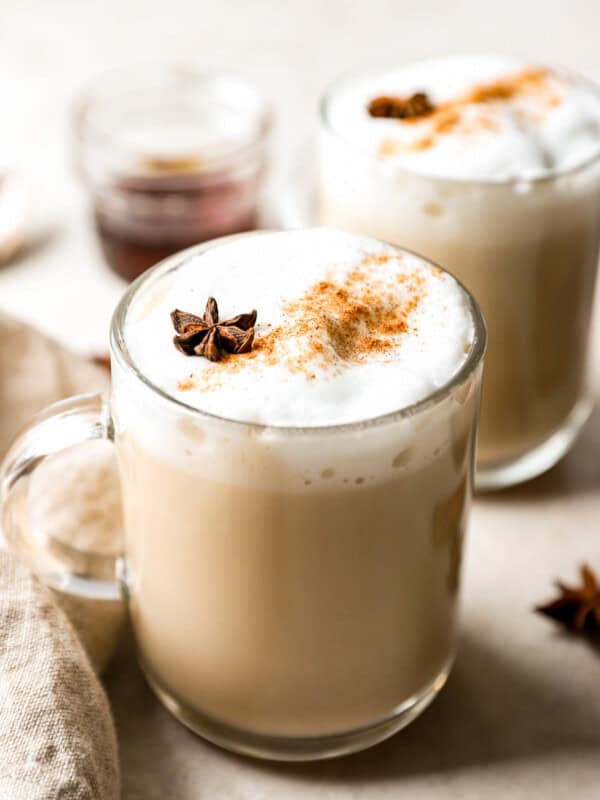 Two mugs of latte with cinnamon and star anise.