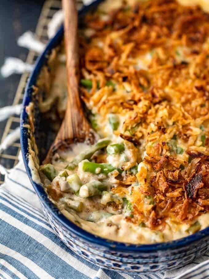 green bean casserole in a blue dish with a wooden spoon.