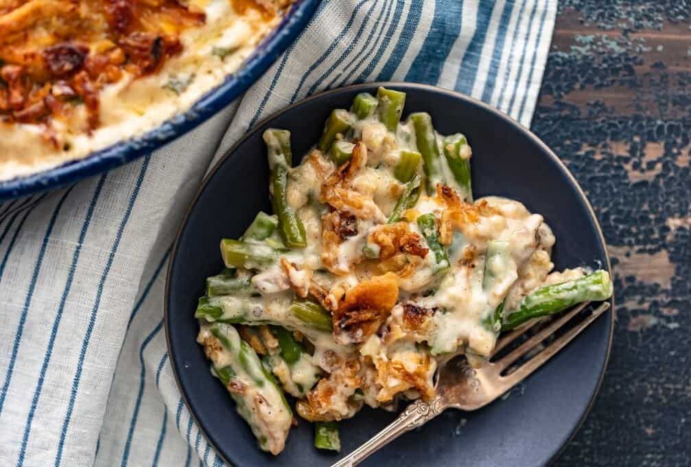 A serving of creamy green beans on a plate with a fork.