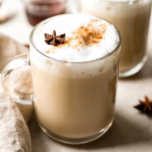 Two mugs of latte with cinnamon and star anise.