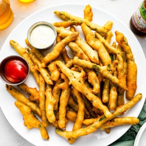 Fried green beans on a plate with dipping sauce.