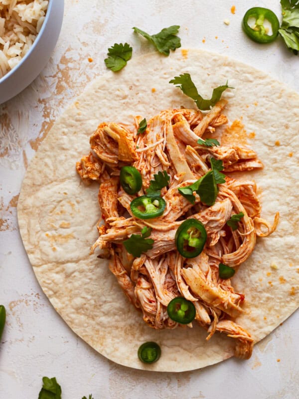 instant pot shredded chicken spread onto a tortilla to make tacos.