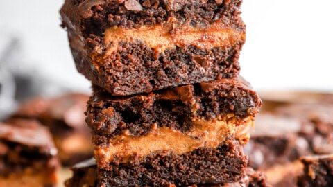 3 pumpkin brownies stacked on a cutting board.