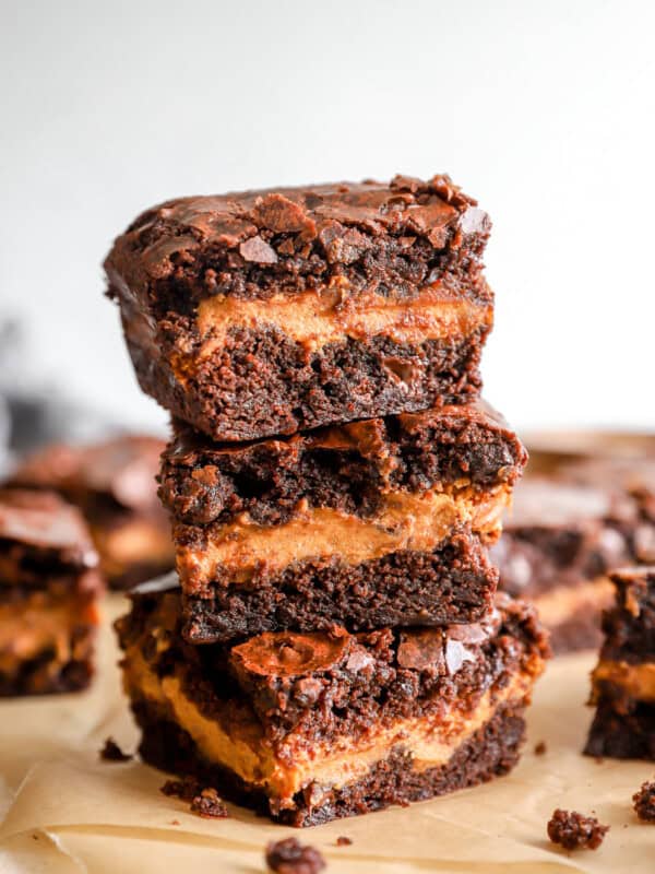 3 pumpkin brownies stacked on a cutting board.