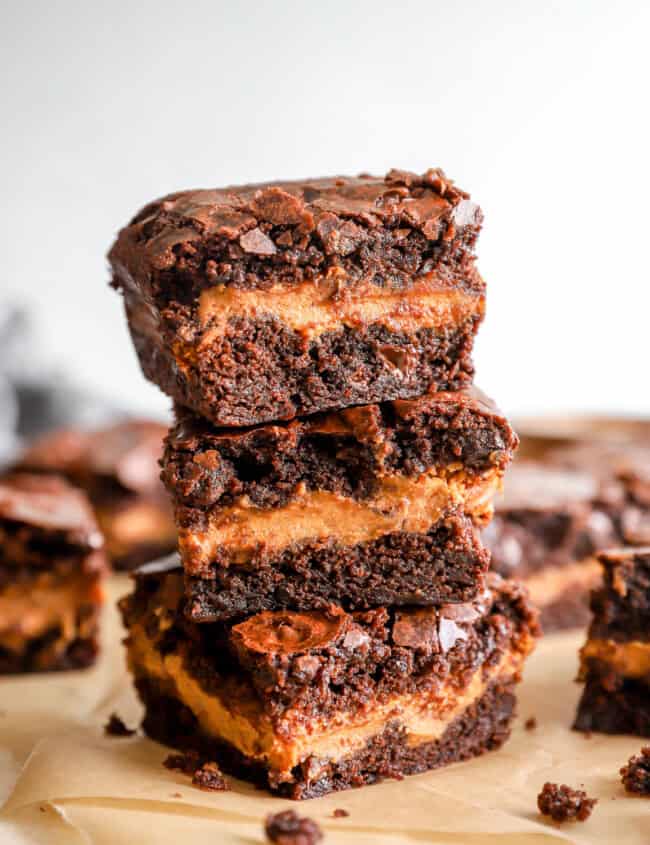 3 pumpkin brownies stacked on a cutting board.