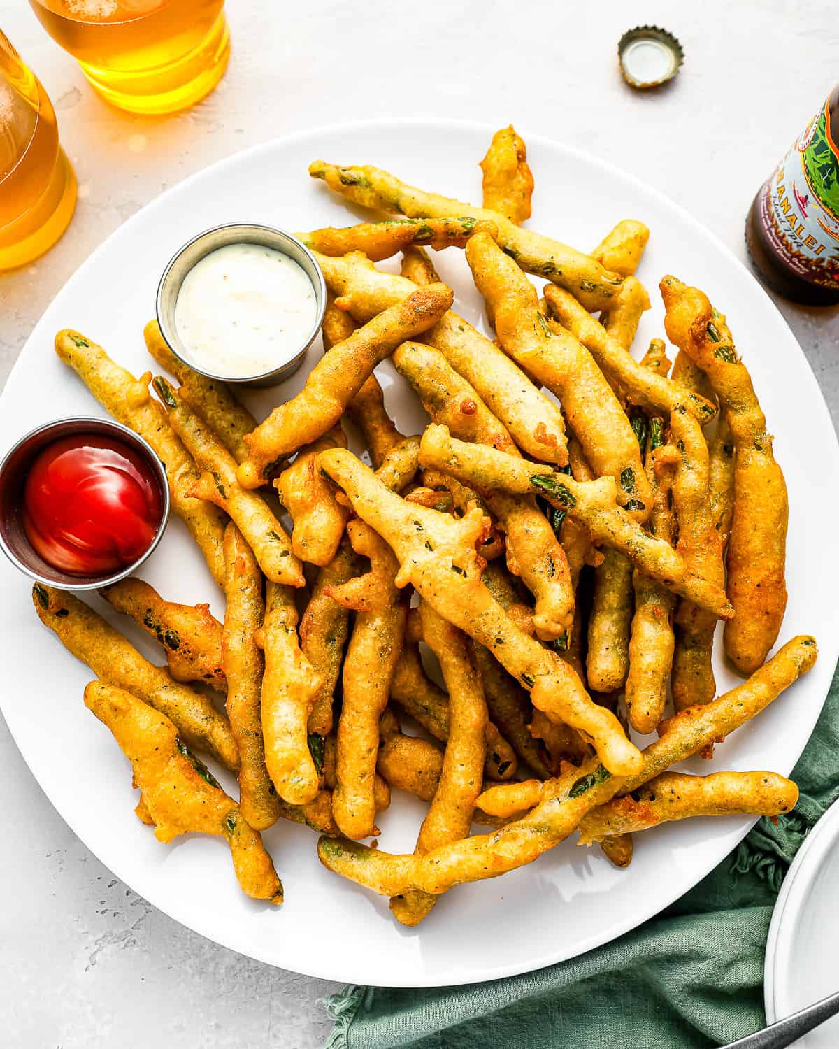 A plate of fried green beans with dipping sauce.