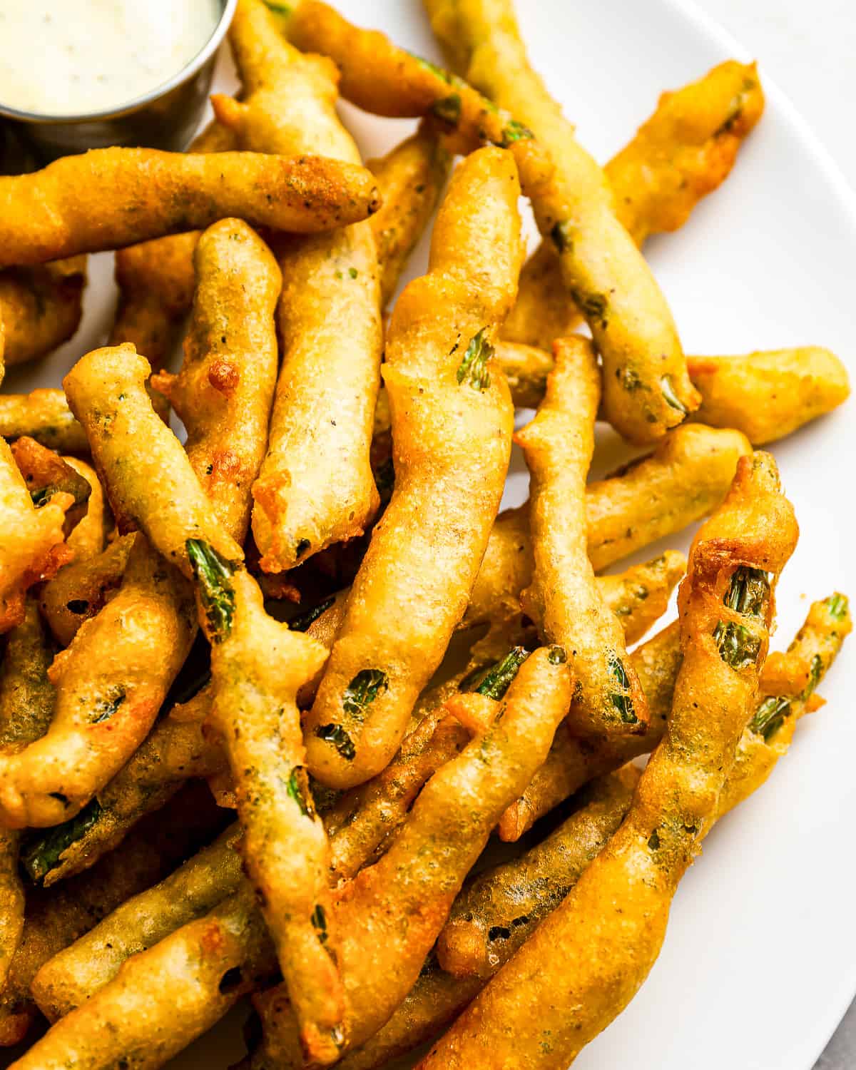 A plate of fried green beans with dipping sauce.