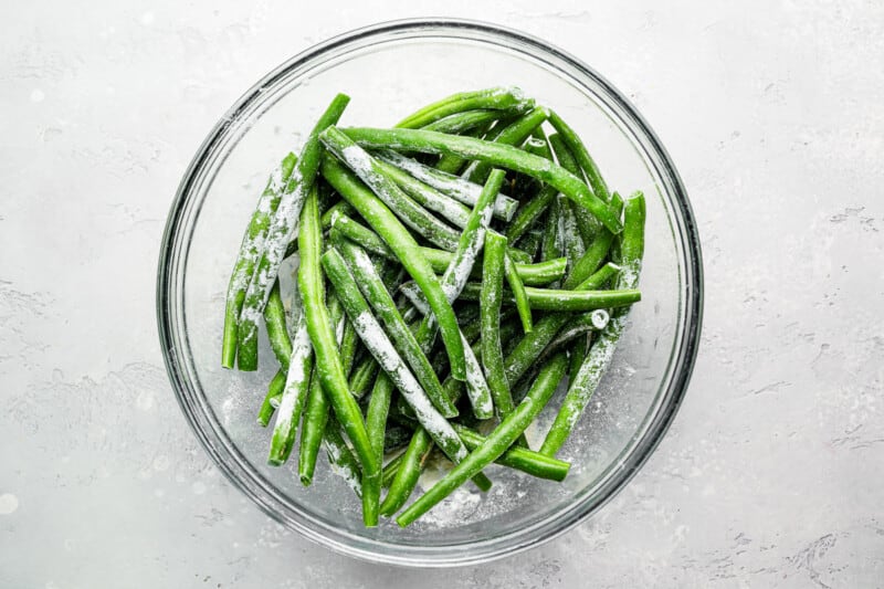 Green beans in a glass bowl on a white background.