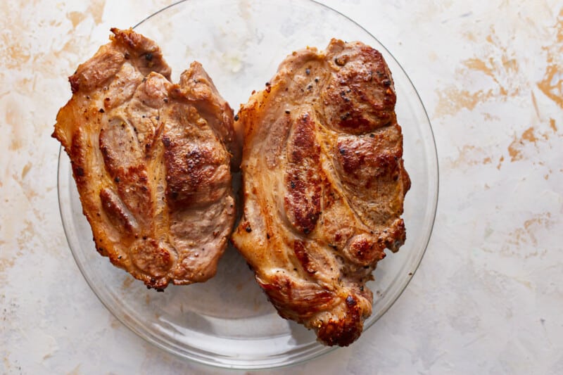 Two pieces of meat on a glass plate.