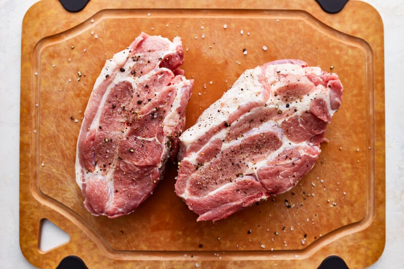 Two pieces of pork on a cutting board.