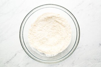 Flour in a glass bowl on a marble table.