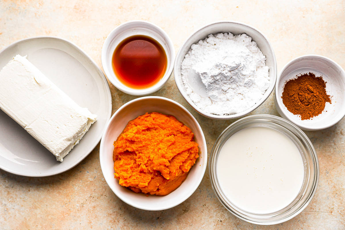 The ingredients for a pumpkin pie are in bowls on a table.