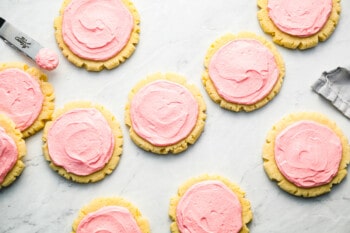 Pink frosted cookies on a marble countertop.
